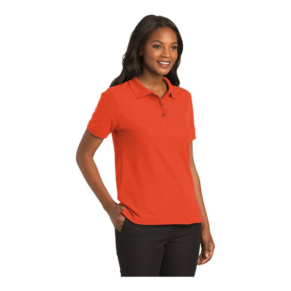 A woman wearing an orange Port Authority polo shirt.