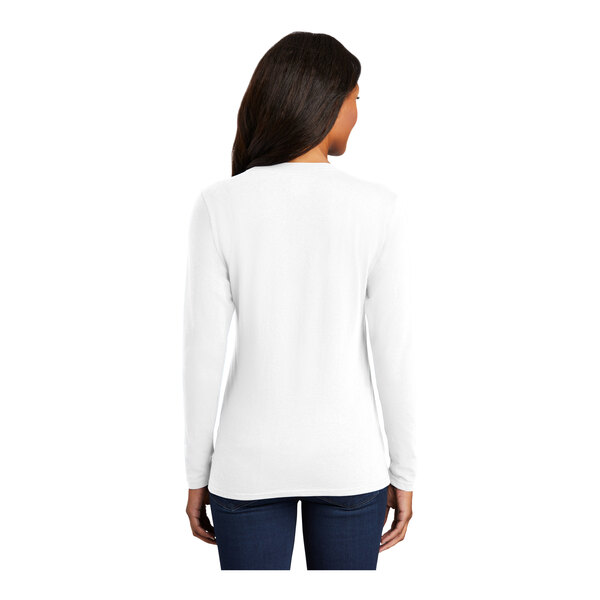 A woman wearing a white Port & Company long sleeve shirt.
