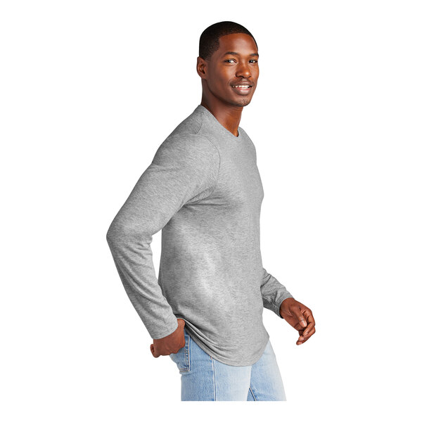 A man wearing a light heather grey long sleeve District t-shirt.
