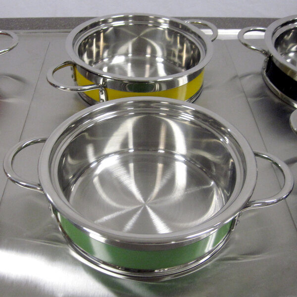 A green Bon Chef steam table pot with riveted handles on a metal surface.