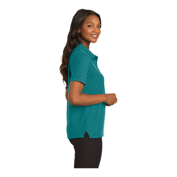 A woman wearing a teal Port Authority polo shirt with short sleeves.