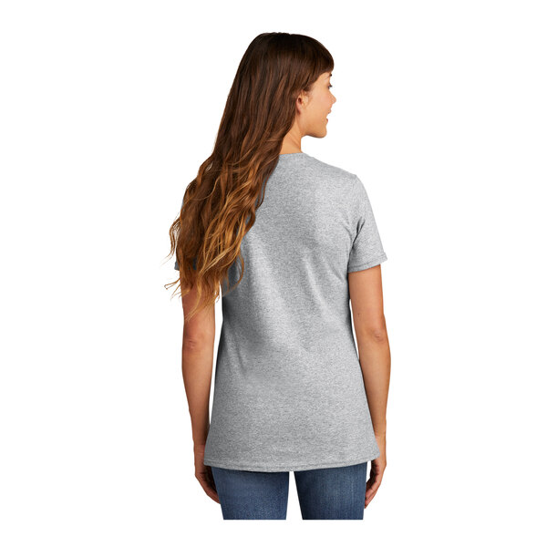 A woman with long hair wearing a grey Port & Company T-shirt.