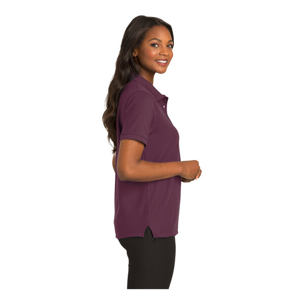 A woman wearing a maroon Port Authority Silk Touch polo shirt.