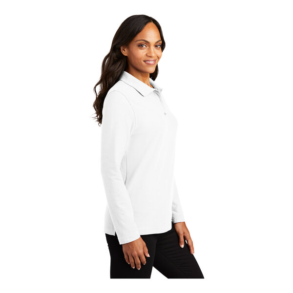 A woman wearing a white Port Authority long sleeve polo shirt.