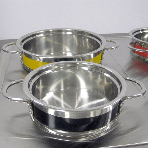 A yellow Bon Chef stainless steel pot with riveted handles.