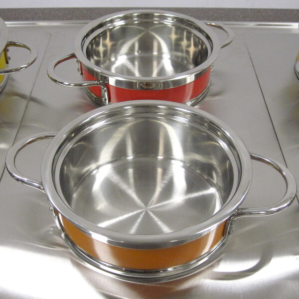 A Bon Chef orange and silver steam table pot on a stove.