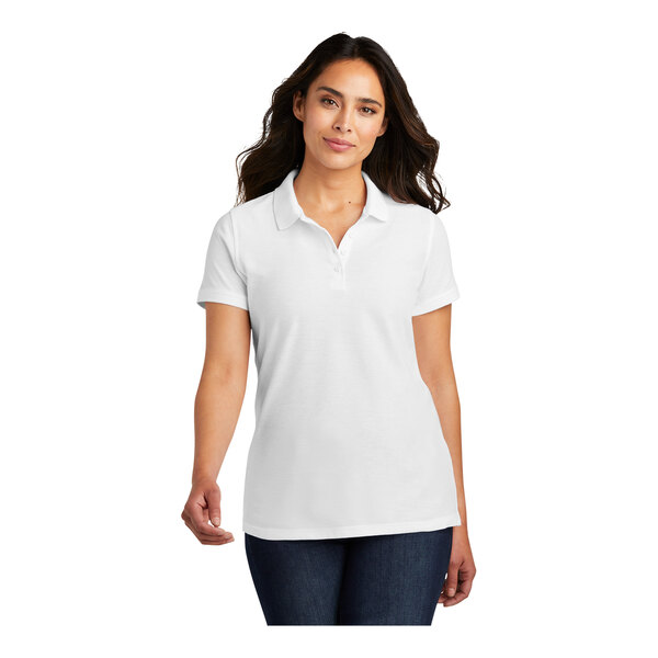 A woman wearing a white Port Authority pique polo shirt.