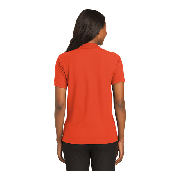 A woman wearing an orange Port Authority polo shirt.