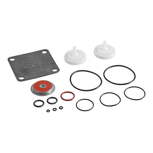 A Watts repair kit with round black and red gaskets, a red and grey disc, and a black square object with white lines.