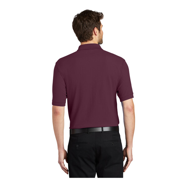 A man wearing a maroon Port Authority silk touch pique polo shirt.