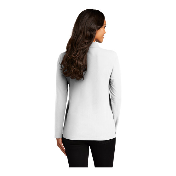 The back view of a white Port Authority long sleeve polo shirt on a woman with long brown hair.