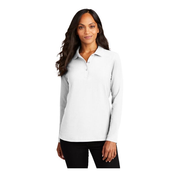 A woman wearing a white Port Authority long sleeve polo shirt.