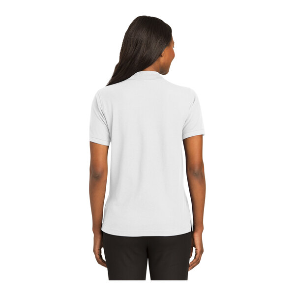A woman wearing a white Port Authority polo shirt.