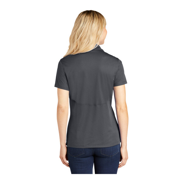 A woman wearing a grey Sport-Tek short sleeve polo shirt.