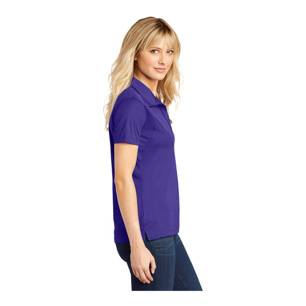 A woman wearing a purple Sport-Tek short sleeve moisture-wicking polo shirt.