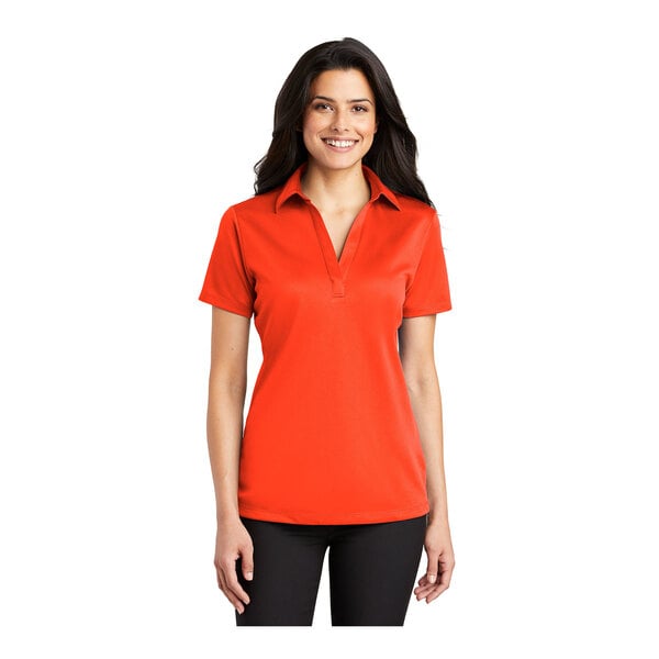 A woman wearing a Port Authority neon orange short sleeve polo shirt.