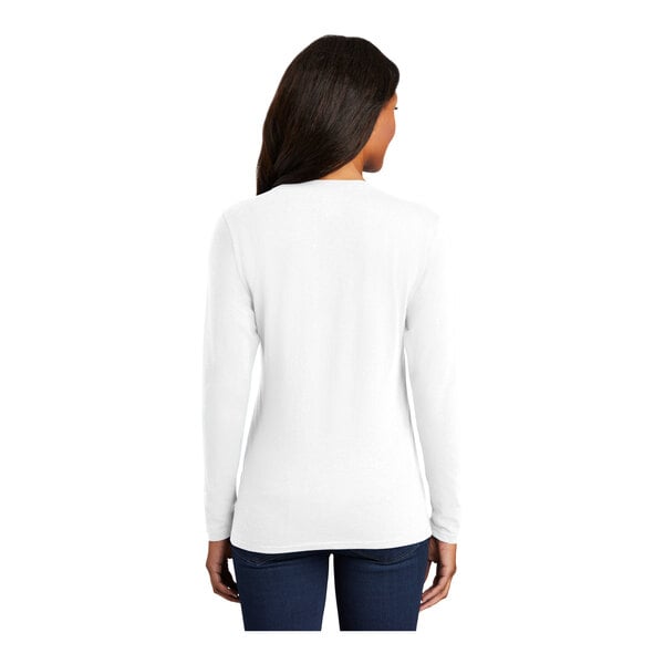 A woman wearing a white Port & Company long sleeve shirt.