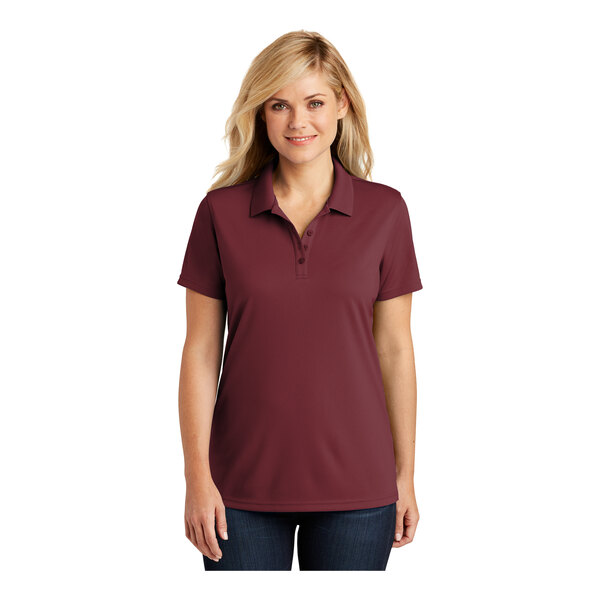 A woman wearing a Port Authority Dry Zone women's maroon polo shirt.