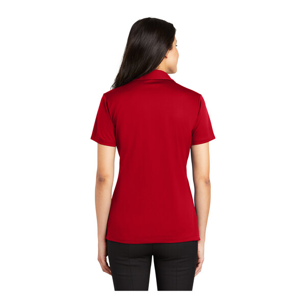A woman wearing a red Port Authority Silk Touch polo shirt.