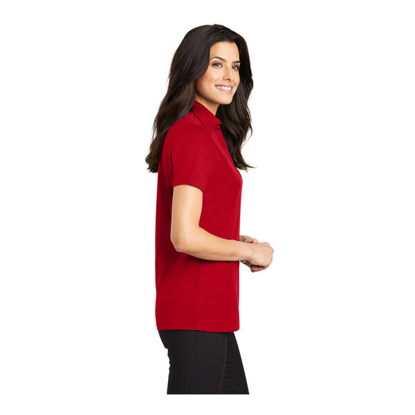 A woman wearing a red Port Authority silk touch polo shirt.