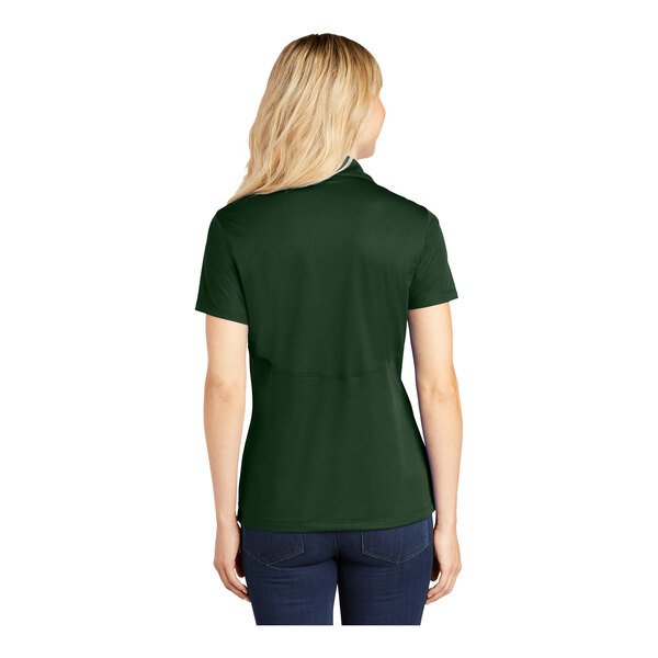 A woman wearing a forest green Sport-Tek polo shirt.