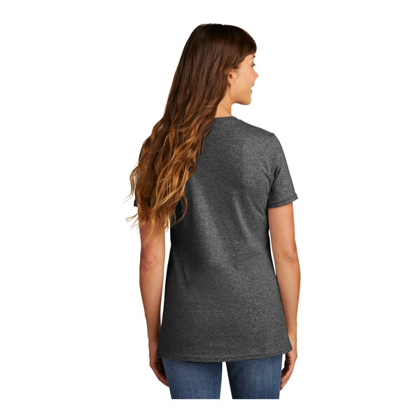 A woman with long brown hair wearing a dark heather grey Port & Company short sleeve t-shirt.
