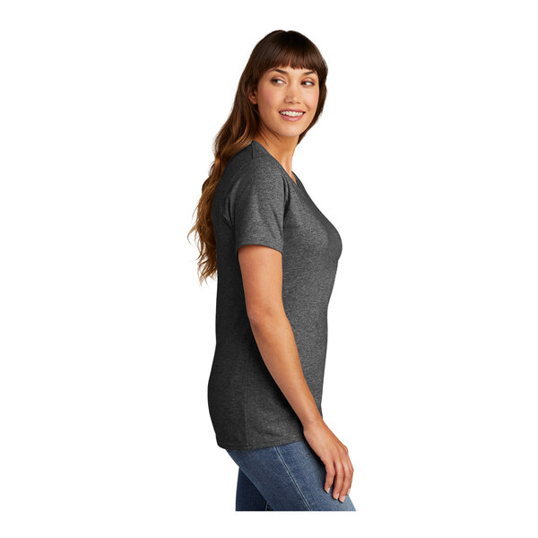 A woman wearing a dark heather grey Port & Company t-shirt.