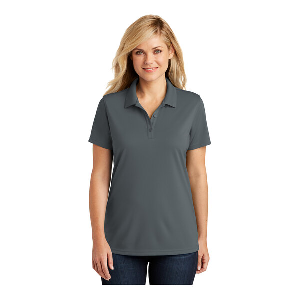 A woman wearing a graphite grey Port Authority Dry Zone polo shirt with a collar.