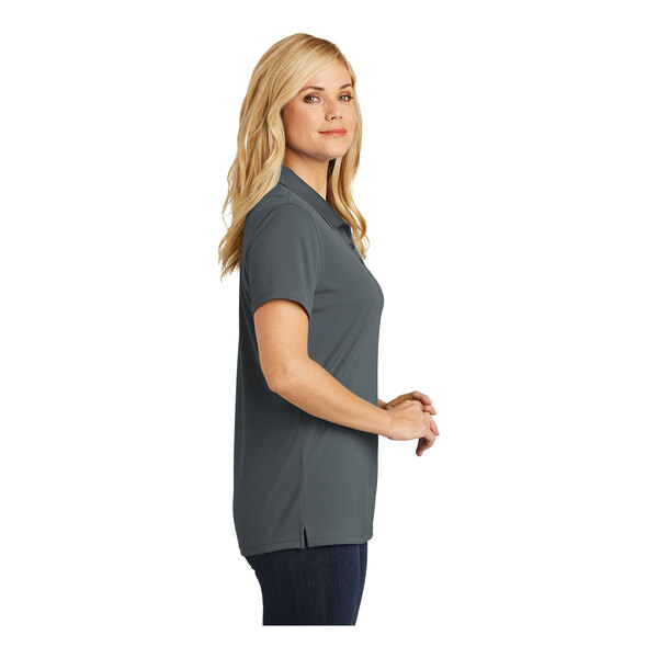 A woman wearing a graphite Port Authority polo shirt.