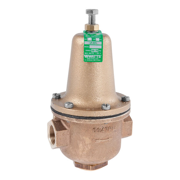 A close-up of a brass Watts high-capacity water pressure reducing valve with a green label.