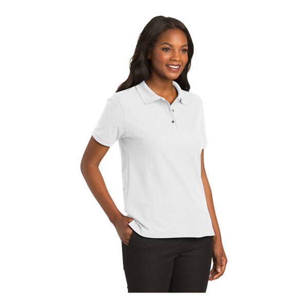 A woman wearing a white Port Authority silk touch polo shirt.