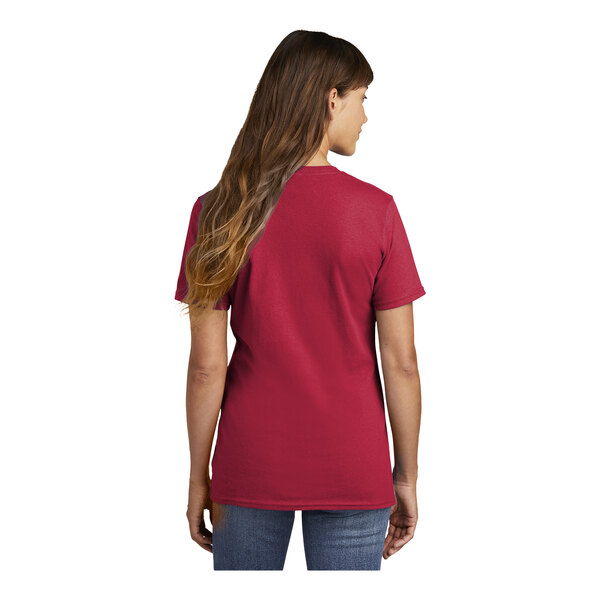 A woman wearing a red Port & Company short sleeve t-shirt.