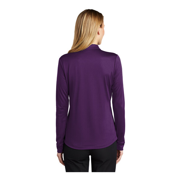 A woman wearing a Port Authority women's bright purple long sleeve polo shirt.