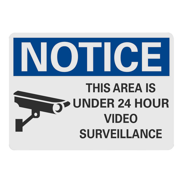 A white plastic sign with black text reading "Notice This Area Is Under 24 Hour Video Surveillance" and a black and white camera symbol.