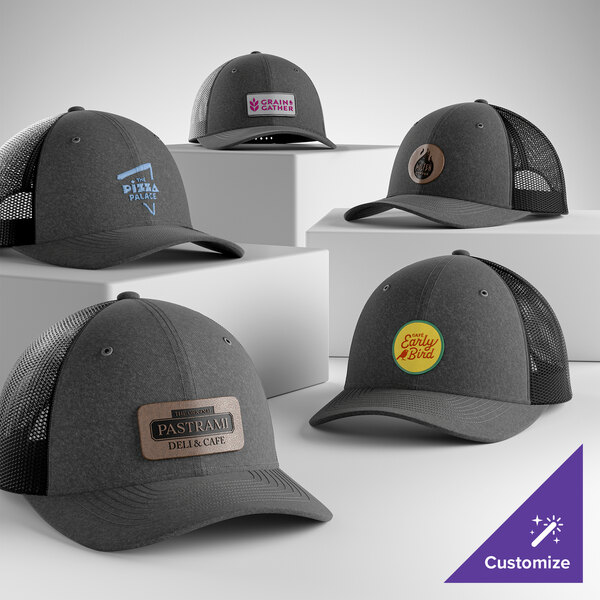 A customizable heather graphite and black 6-panel trucker cap with a mesh back and various logo options displayed.