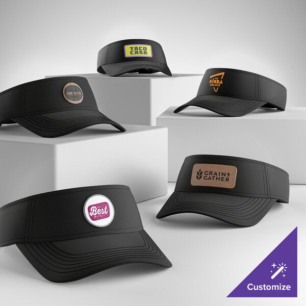 A collection of black moisture-wicking visors with customizable front patches displayed on white blocks.