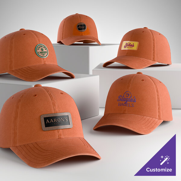 A collection of orange, customizable, unstructured six-panel dad caps with various business logos displayed on them.