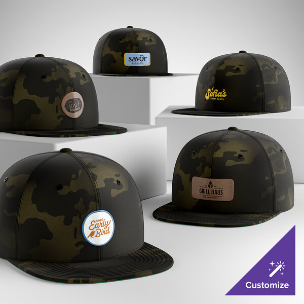 A collection of customizable black camouflage flat bill snapback caps with various logo patches on the front.