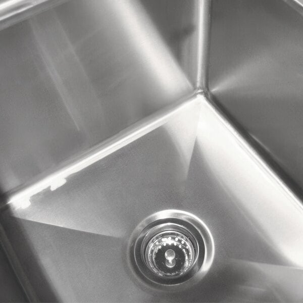 A stainless steel Advance Tabco three compartment sink on a counter.