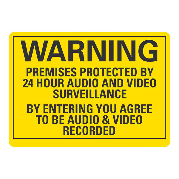 A yellow warning sign with black text that says "Premises Protected By 24 Hour Audio And Video Surveillance"