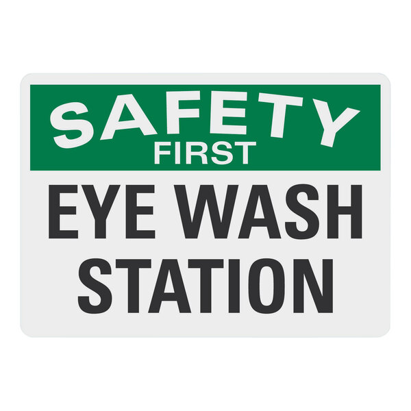 A white rectangular plastic sign with green and white text that says "Safety First / Eye Wash Station"
