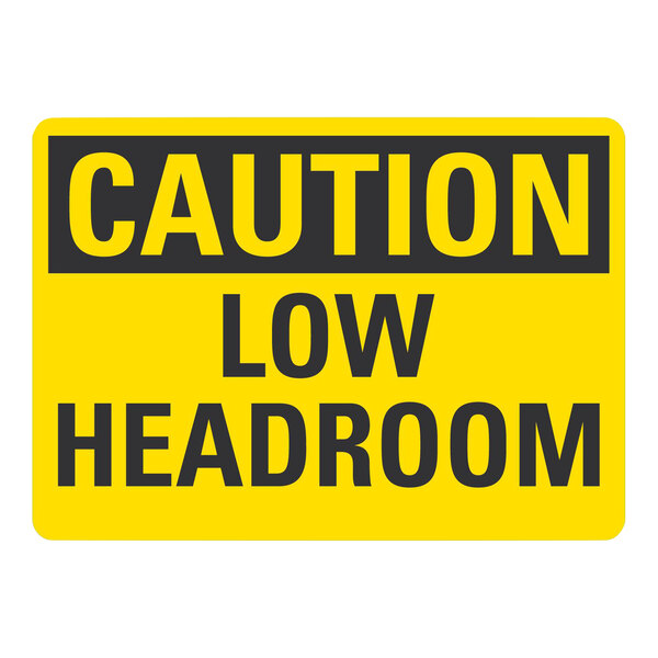 A yellow plastic sign that says "Caution Low Headroom" in black text.