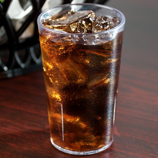 A Cambro clear plastic tumbler filled with ice tea on a table.