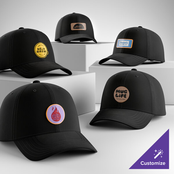 A collection of customizable black 6-panel dad caps with various logo patches displayed on white platforms.