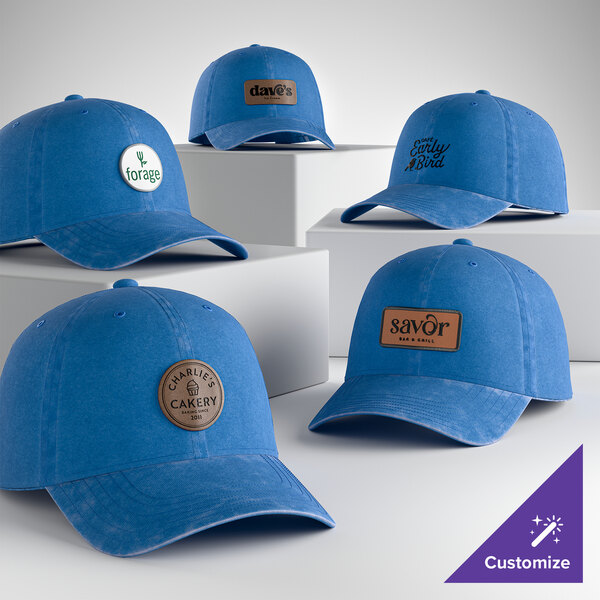 A collection of customizable blue unstructured low-profile dad caps with various logo patches on the front.