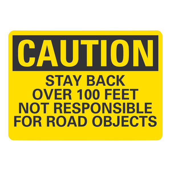 A yellow sign with black text that says "Caution / Stay Back Over 100 Feet / Not Responsible For Road Objects"