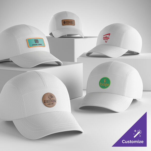 A collection of customizable white 5-panel mesh athletic caps with various logo patches on the front.