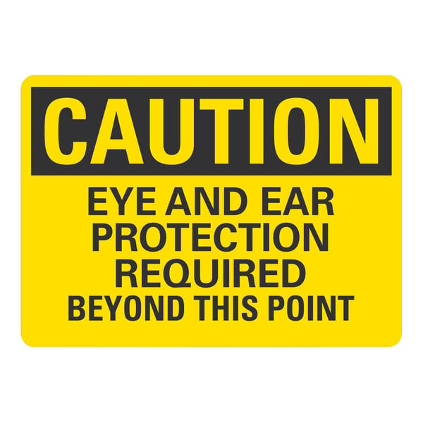 A yellow sign with black letters that says "Caution Eye and Ear Protection Required Beyond This Point"