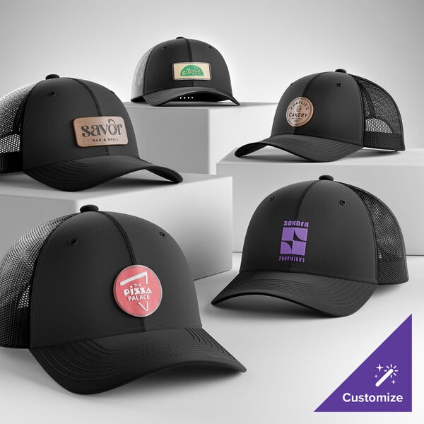 A collection of customizable black 6-panel trucker caps with mesh backs, each featuring different logo designs on the front.