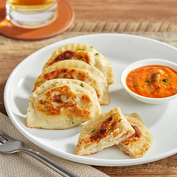 A plate with two Jaju Potato and Cheese Pierogies with a fork.